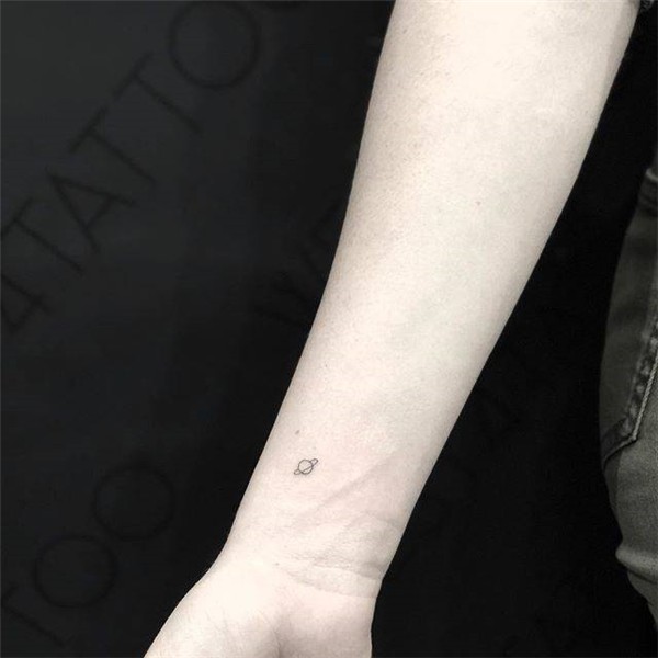 Minimalist saturn tattoo on the wrist.