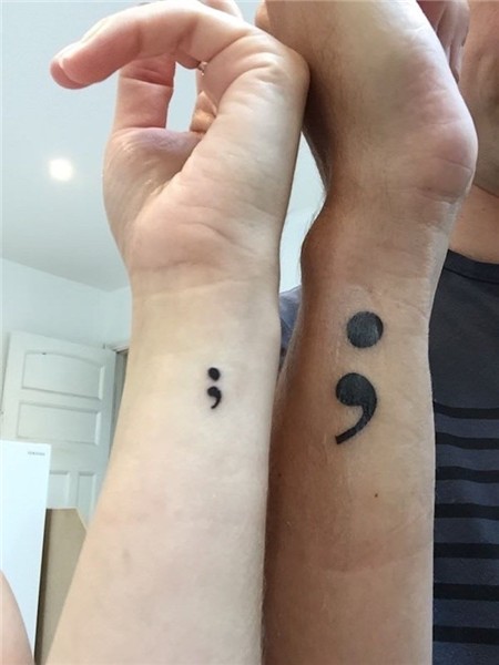 male hand with large black semicolon tattoo, and female hand